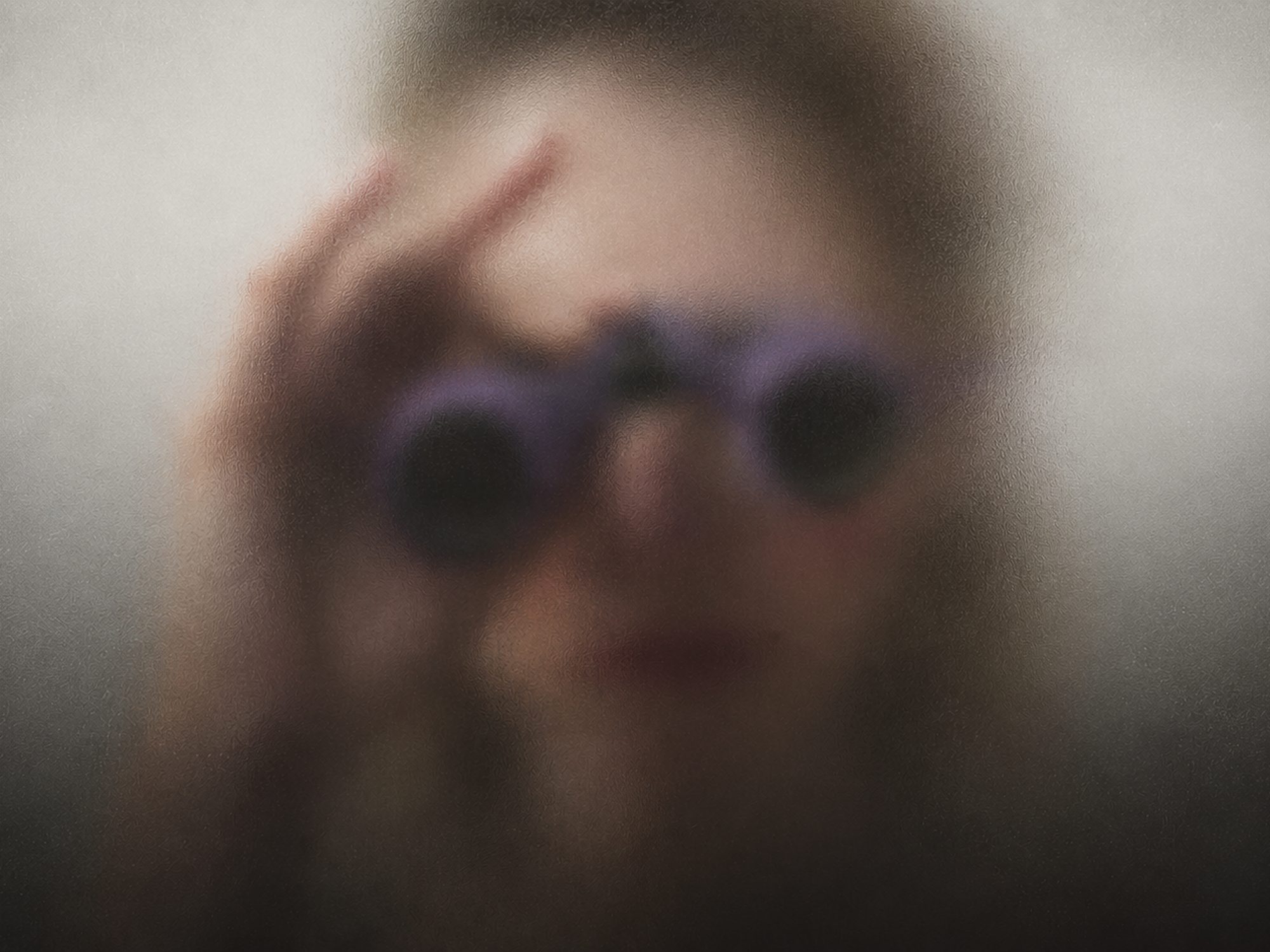 A woman behind frosted glass, holding binoculars